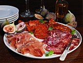 A platter of cold cuts with figs and basil