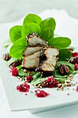 A salad with baby spinach, red-wine chicken, lingonberries and roasted pecan nuts