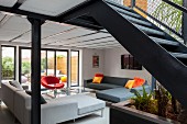 Elegant lounge area with corner sofas in front of terrace doors with steel staircase in foreground