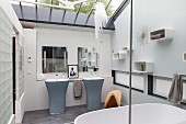 Elegant designer bathroom in subtle shades with twin pedestal sinks and glass ceiling