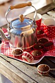 Mini chocolate muffins with a tea can and cups on a tray