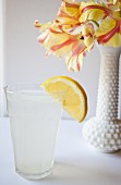 Ein Glas Zitronenwasser neben Blumenvase