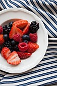 Mixed berries in a white bowl on a striped cloth