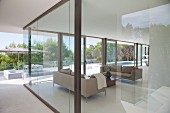 View of elegant living area, terrace and pool through glass walls