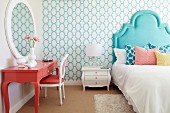 Bed with turquoise headboard and salmon-pink dressing table in bedroom