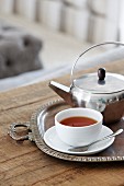 Teacup and silver teapot on tray on rustic wooden table