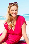 Blonde Frau in pinkfarbenem Strandkleid am Meer