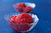 Strawberry sorbet in glass bowls on a blue surface