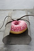 A raspberry-glazed doughnut wrapped in tissue paper