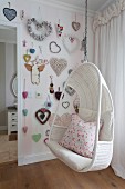 White wicker hanging chair and heart-shaped decorations on wall in girl's bedroom