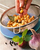 Cooked chickpeas with a bay leaf in a sieve