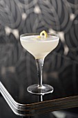 Lemon Drop Cocktail mit Zitronenschale auf Tisch im Art Deco Stil