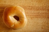 A bagel on a wooden board (seen from above)