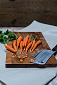 Carrots and parsley with a meat cleaver on a chopping board