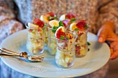 Potato salad with salami and quail's eggs in glasses