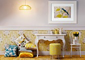 White console table next to stack of cushions and Thonet chair against wall with yellow wallpaper below dado rail