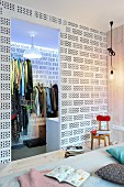 View from bed into walk-in wardrobe made from white-painted hollow bricks