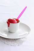 Redcurrant ice cream in a cup with a plastic spoon
