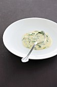 Bearnaise sauce with herbs on a plate with a spoon