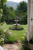 Blick auf Springbrunnen aus Stein in weitläufigem Garten