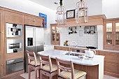 Breakfast bar and bar stools in open-plan kitchen with pale wooden cabinet in modern, country-house style