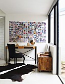 Console table and black-upholstered chair below photo collage on wall