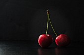 Two cherries on a black surface