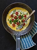Omelette with cherry tomatoes, spring onions and basil
