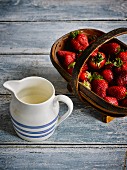 Fresh strawberries in a basket next to a jug of milk