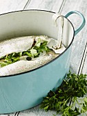 Herb-filled trout being prepared in a pot