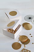Hand-crafted cardboard boxes for storing punched gold confetti