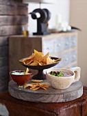 Tortilla chips with a bean dip and a sour cream dip on a wooden board