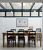 Rustic wooden dining table and chairs in extension with glass roof