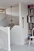 Head of staircase with white, solid balustrade and bookcase to one side