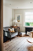 Antique sofa next to classic table lamp on vintage table in rustic living room with wooden floor