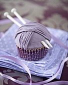 A ball of wool cupcake decorated with a knitting needles