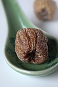 A dried jujube fruit on a ceramic spoon