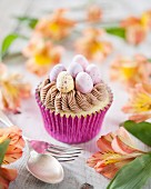 An Easter cupcake decorated with chocolate cream and mini chocolate eggs