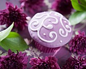 A purple cupcake decorated with a filigree pattern