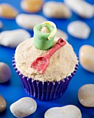 A beach cupcake decorated with bucket and spade