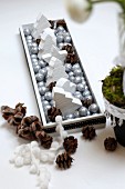 Wooden tray festively decorated with silver baubles, wooden Christmas trees & pine cones