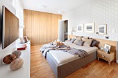 Schlafzimmer mit Doppelbett auf hellem Holzboden, im Hintergrund eingebauter, hermetischer Holzschrank
