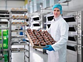 Bäcker zeigt Tablett mit Kuchen in der Kuchenfabrik