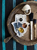 Pots of spices on hamsa-shaped tray, paintbrushes and shells on old wooden tray