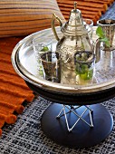 Silbertablett mit marokkanischer Teekanne und Gläsern auf modernem Beistelltisch