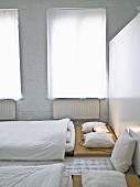 Japanese-style sleeping area with white curtains on windows and whitewashed brick wall