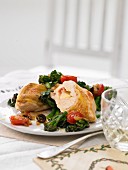 Cheese-filled corn-fed chicken on rapini with cherry tomatoes and olives