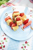 Colourful fruit skewers on a plate in a garden