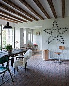 Vintage chairs on paved floor in dining area and star-shaped lamp on wall next to open doorway in rustic interior