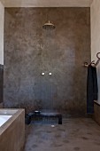 Dusche im Ethnostil mit grau verputzten Wänden und prasselndem Wasser